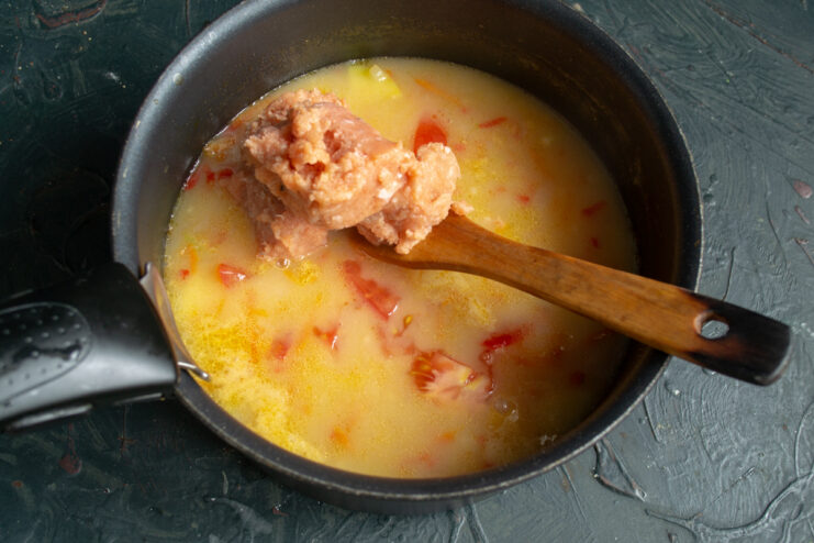 Adding salmon Placing minced salmon into the boiling hot soup base