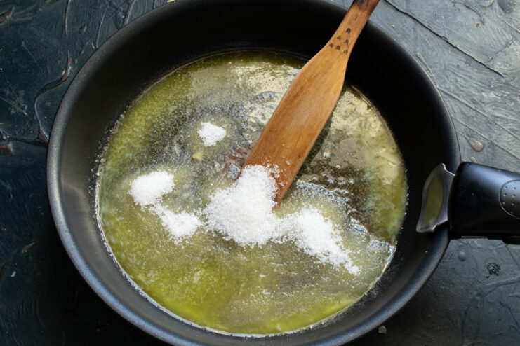 Adding sugar into melted butter in a hot skillet.