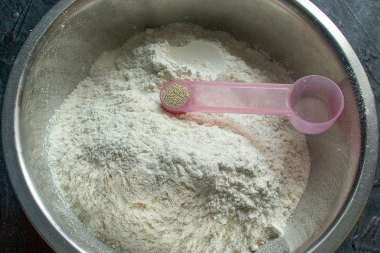 Adding instant dry yeast to a bowl of sifted flour
