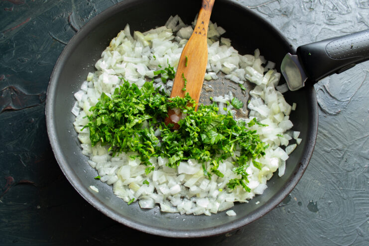 Adding Fresh Herbs Stirring chopped fresh parsley into sautéed onions in a skillet