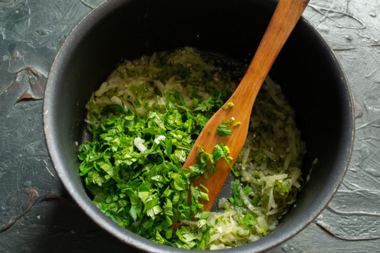 Adding fresh herbs Adding freshly chopped parsley and celery leaves to sautéed onions