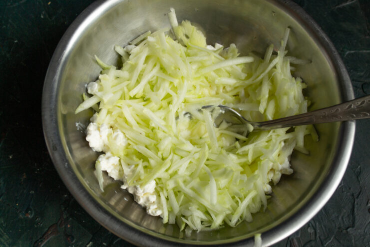 Adding grated zucchini Adding freshly grated zucchini to the cheese and egg mixture