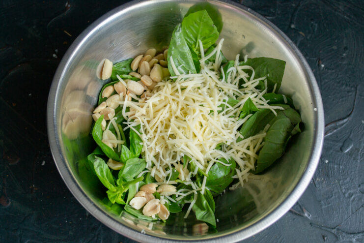 Adding cheese to the mix Mixing grated hard cheese into the fresh basil and peanuts