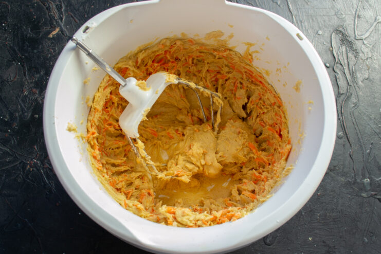 Adding carrots and peanuts Folding grated carrots and chopped peanuts into the dough