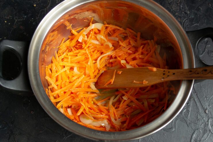 Simmering carrots and onions Adding grated carrots to sautéed onions in a heavy-bottomed pot