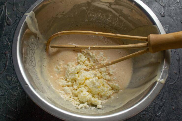 Folding farmers cheese into the egg mixture in a bowl