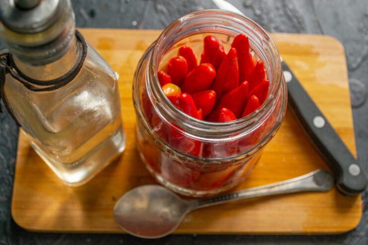 Adding the vinegar Pouring apple cider vinegar into a jar of hot peppers