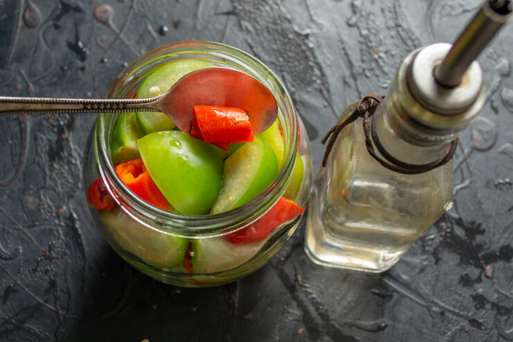 Adding the vinegar Pouring apple cider vinegar into a jar filled with vegetables