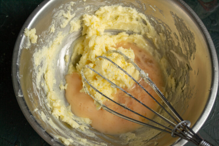 Adding the Egg Pouring beaten egg mixture into creamed butter in a metal bowl