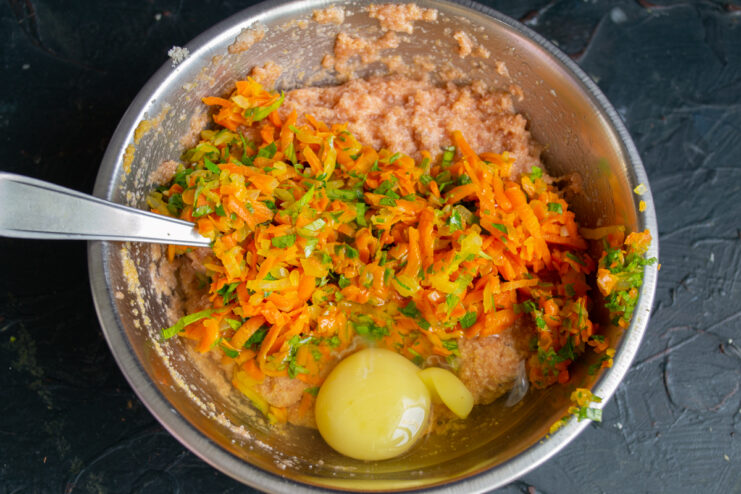 Adding a raw egg and chopped vegetables to the fish mixture