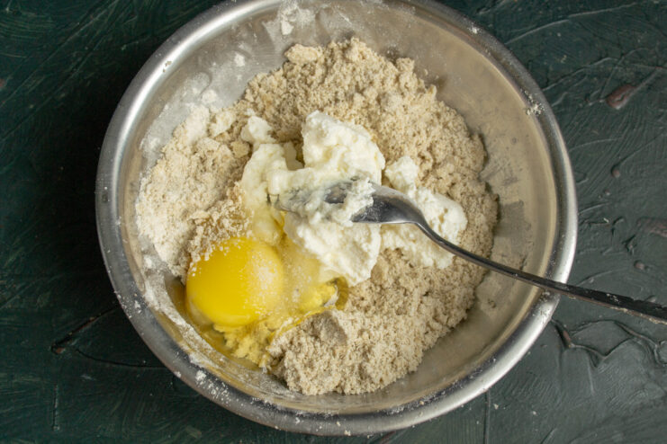 Adding Wet Ingredients Adding an egg and ricotta to the flour crumb mixture