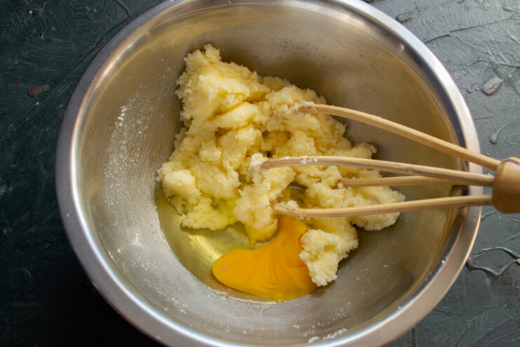 Adding wet ingredients Whisking a raw egg into the creamed butter mixture