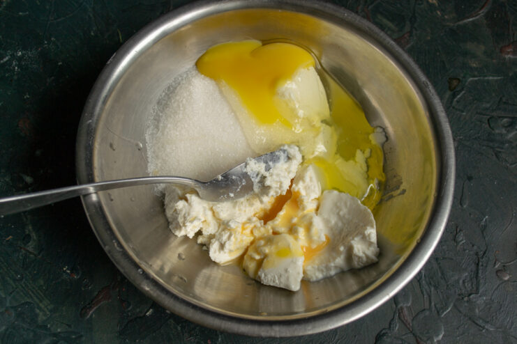 Adding eggs to the filling Adding an egg to the sweet ricotta mixture in a bowl