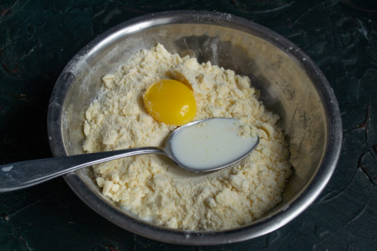 Adding Wet Ingredients Adding egg yolk and milk to the flour and butter crumb mixture