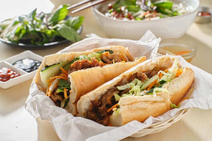Vietnamese banh mi sandwiches with meat and vegetables Two Vietnamese banh mi baguettes filled with meat and pickled vegetables in a basket.