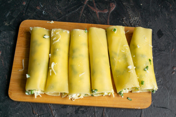 Stuffing the cannelloni Cheese stuffed cannelloni tubes resting on a wooden board