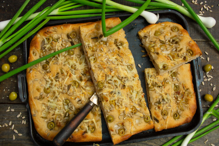 Baked sourdough focaccia with cheese, olives, and onions
