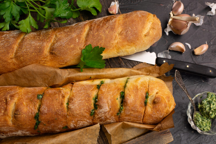 Golden French bread stuffed with garlic and herbs on a dark background