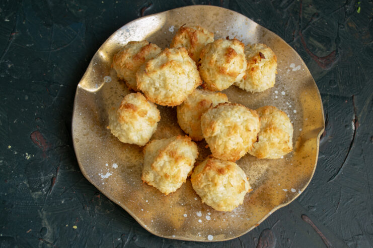 Serving the baked coconut cookies. A small pile of golden baked coconut macaroons resting on a plate.