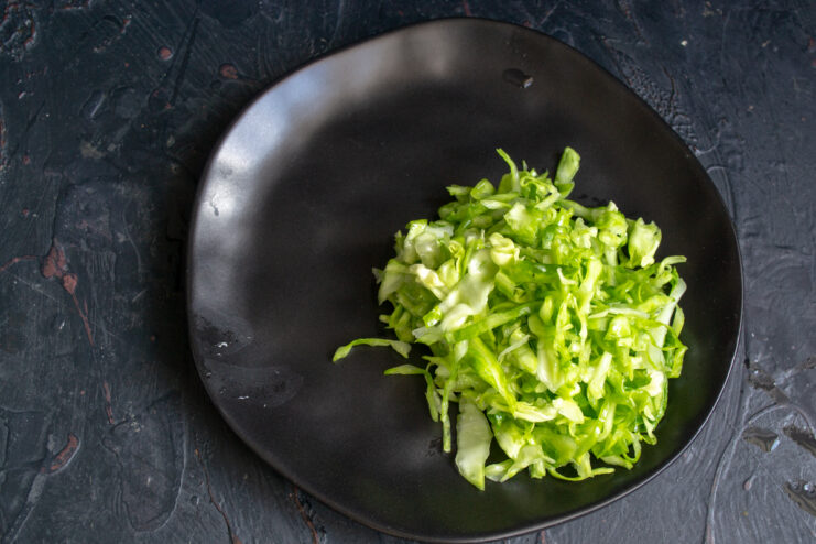 Mound of shredded fresh cabbage on a black plate