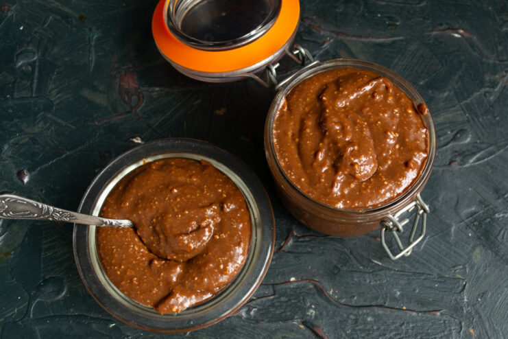 Finished spread in jars Prepared peanut butter in glass jars with a spoon