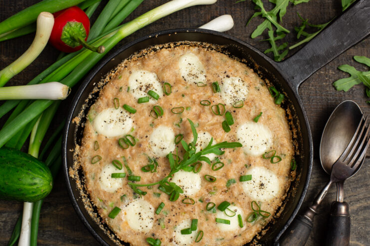 Baked fish casserole with melted mozzarella and fresh herbs in a skillet.