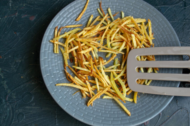 Golden shoestring potatoes Cooked crispy shoestring potatoes on a plate