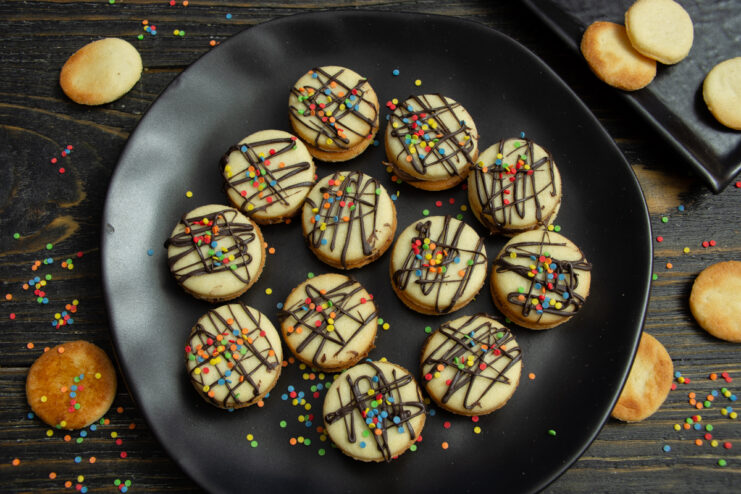 Finished chocolate sandwich cookies topped with chocolate drizzle and colorful sprinkles