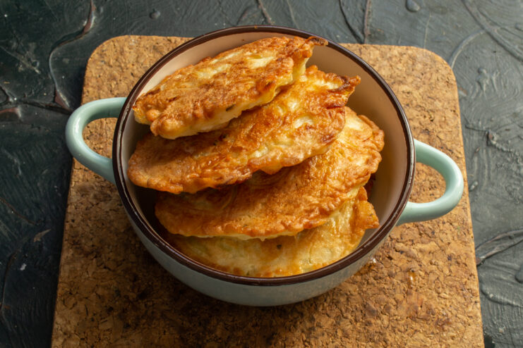 Serving onion fritters Freshly fried tsybulnyky in a ceramic bowl on a stand.