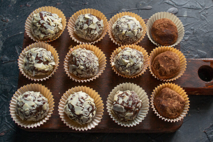 Final touches and coating Rolling formed chocolate truffles in a coating of cocoa powder and chopped almond flakes
