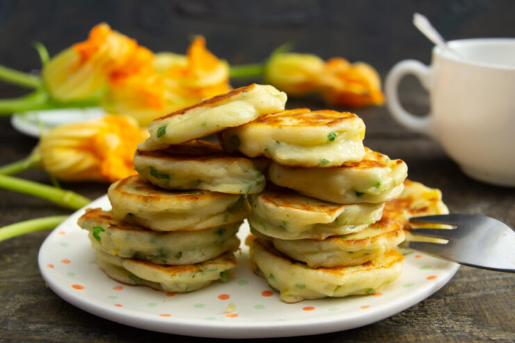 Finished fritters on a polka dot plate surrounded by zucchini blossoms