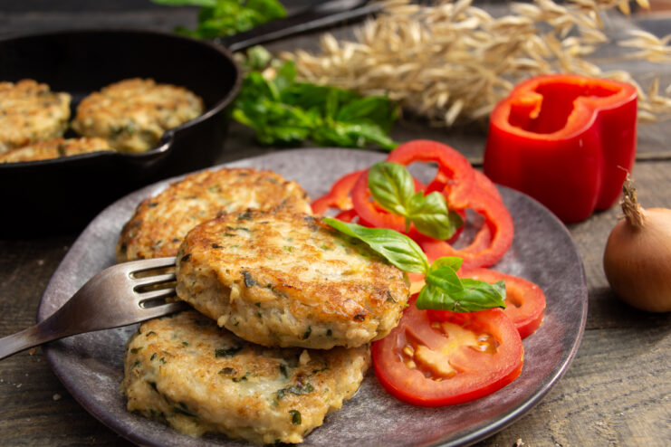 Golden oat patties with onions and egg served on a plate with fresh vegetables