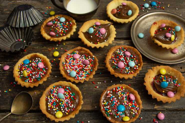 Finished shortcrust pastry tartlets with chocolate cream and vibrant sugar sprinkles