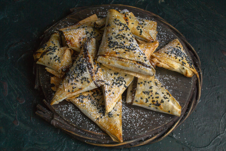 Serving Sweet Samosas Finished sweet poppy seed samosas dusted with powdered sugar on a dark background