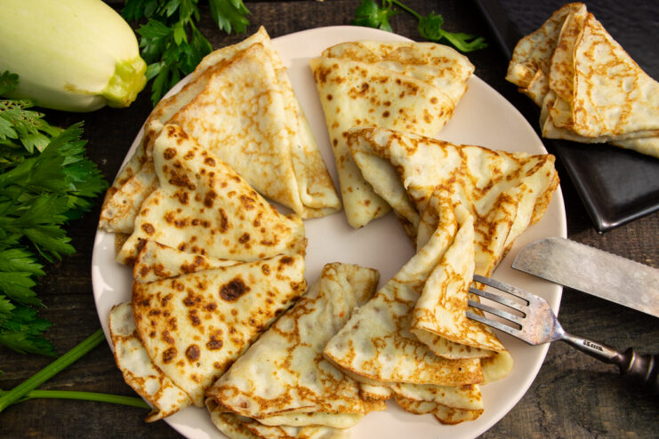 Finished thin zucchini crepes stacked on a plate