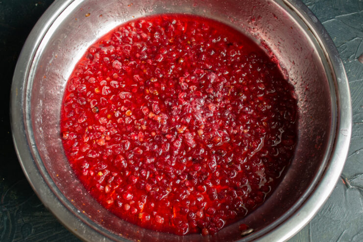 Thick and vibrant lingonberry jam resting in a saucepan
