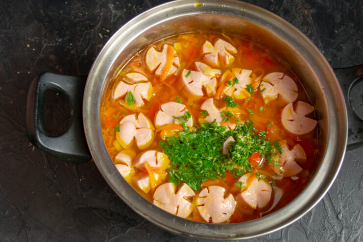 Final touch with fresh herbs Finished sausage soup in a pot generously sprinkled with chopped fresh parsley