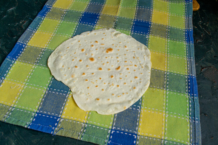 Freshly cooked lavash resting under a kitchen towel