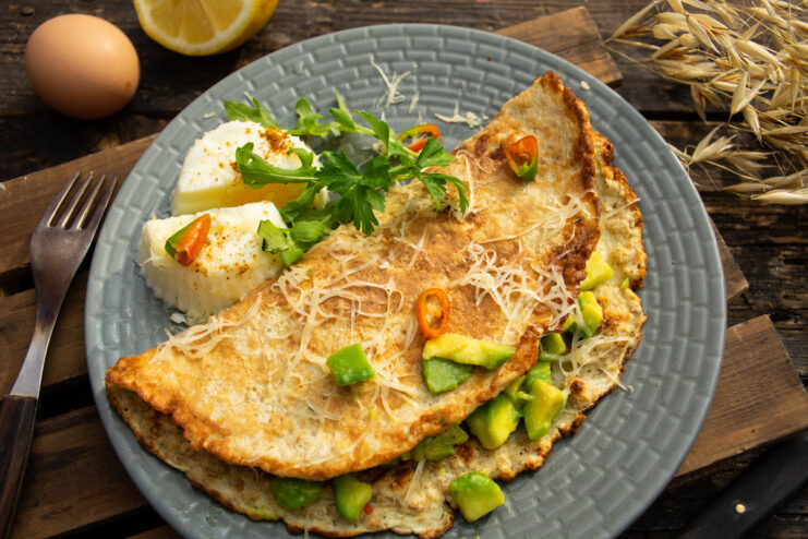 Plated savory oat pancake folded over avocado filling served with a soft poached egg