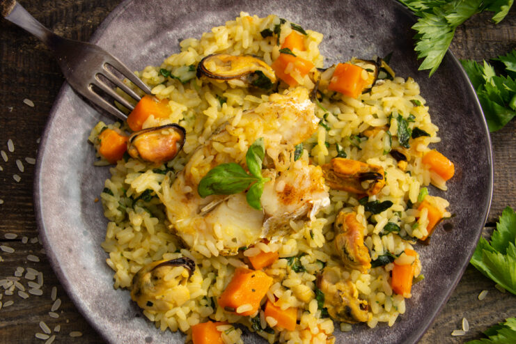 Prepared fish plov with mussels and a sprig of fresh basil