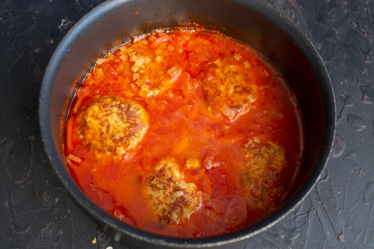 Simmering With Pasta Simmering tomato soup with meatballs and small star pasta in a pot.