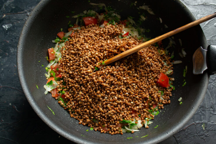 Sautéing Buckwheat with Vegetables Buckwheat mixed with vegetables in a skillet
