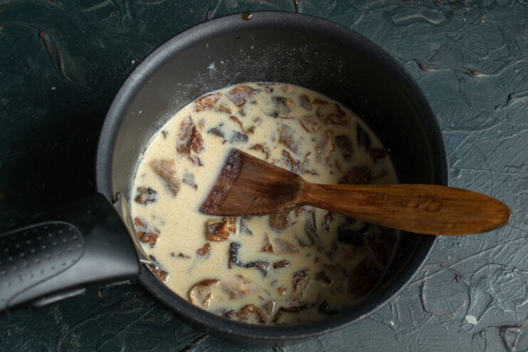 Finishing the Mushroom Sauce Creamy mushroom sauce with chopped porcini simmering in a saucepan.