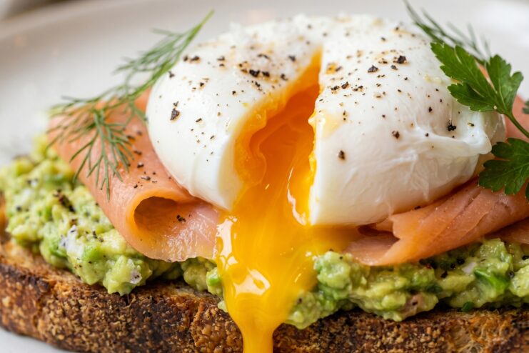 Poached Egg on Toast Perfect poached egg on avocado and salmon toast, with golden liquid yolk slowly spreading over the crusty bread.