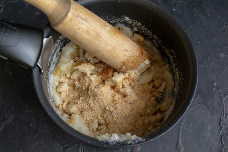 Mashing the beans and breadcrumbs Mashing white beans and breadcrumbs together with a wooden potato masher