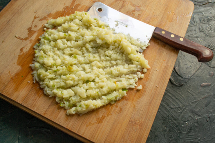 Mincing The Vegetables Mincing cauliflower and onions with a meat cleaver on a wooden board