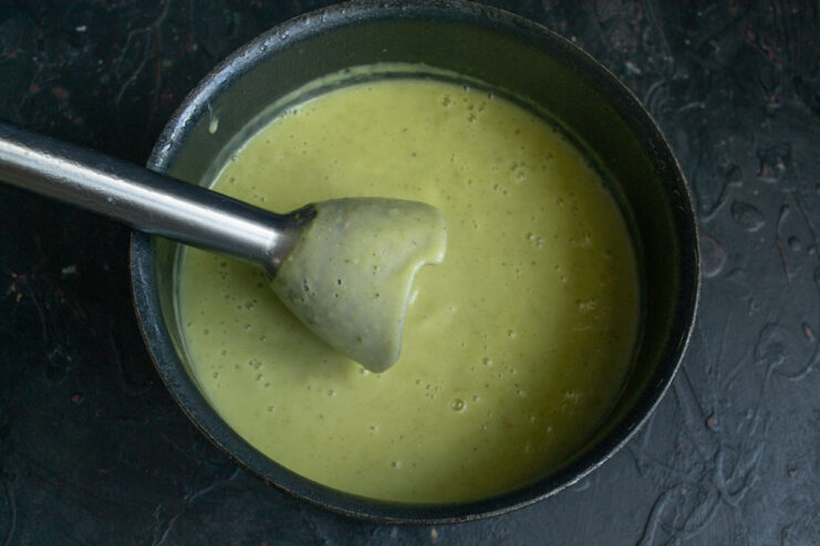 Blending the vegetable soup with an immersion blender into a smooth purée