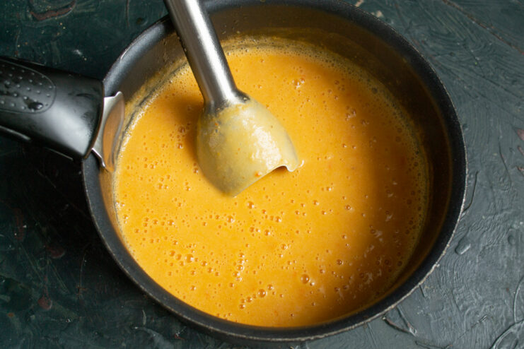 Blending the soup Pureeing the fish soup with an immersion blender until completely smooth