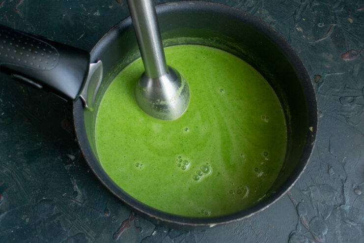 Blending the soup into a silky puree using an immersion blender