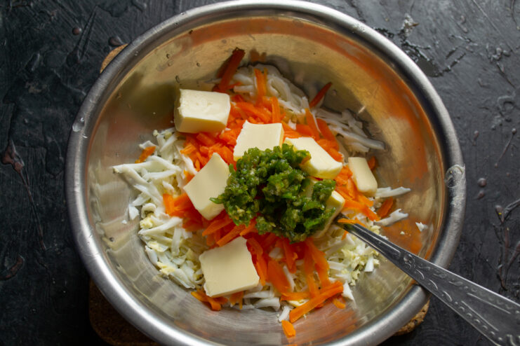 Chopped fresh herbs added to the bowl with vegetables and butter.